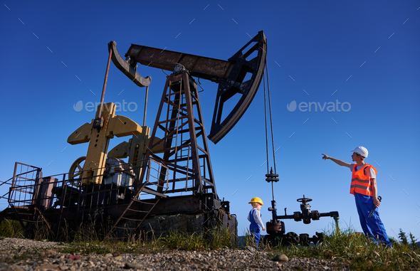 Mechanic showing operation of petroleum rig to small male child.