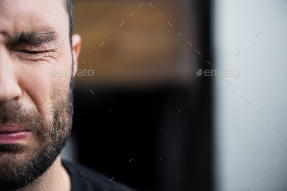 partial view of depressed bearded man crying with closed eyes