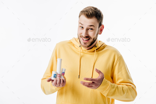 excited young man in yellow hoodie holding containers with social media logos isolated on white