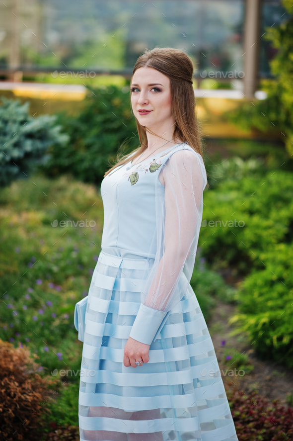 Portrait of an attractive young woman graduate in fancy dress posing in the park.