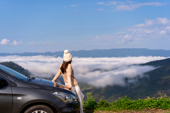 Young woman travelers with car watching a beautiful sea of fog over the mountain