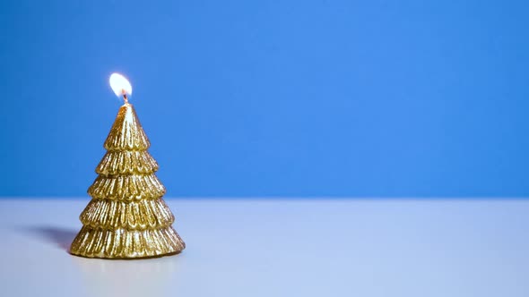 Golden Christmas Tree Wax Candle Burning on Blue Background New Year or Christmas Video Banner with