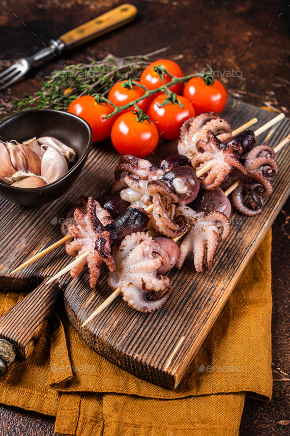 Skewers with bbq roasted baby octopuses. Dark background. Top view