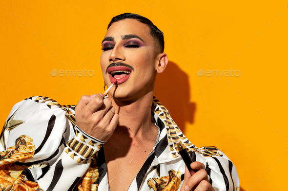 beautiful fashion drag queen model painting her lips.