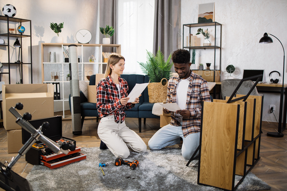 Multicultural couple reading furniture instruction at home