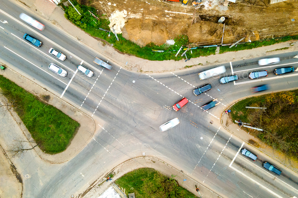 Top down aerial view of busy street intersection with moving cars traffic