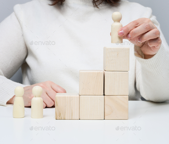 Woman in a white sweater puts a wooden figurine on the podium