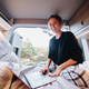 Positive young freelancer with netbook on caravan bed - PhotoDune Item for Sale