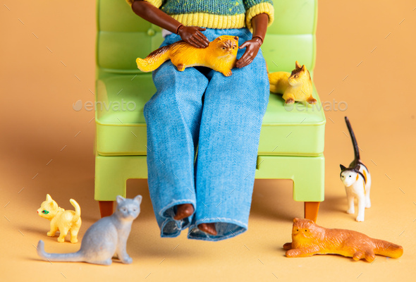 Cat lady with a lot cats in a armchair. Scene with dolls