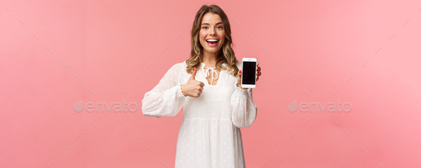 Portrait of upbeat good-looking blond woman in white dress, recommend download app or subscribe - Stock Photo - Images