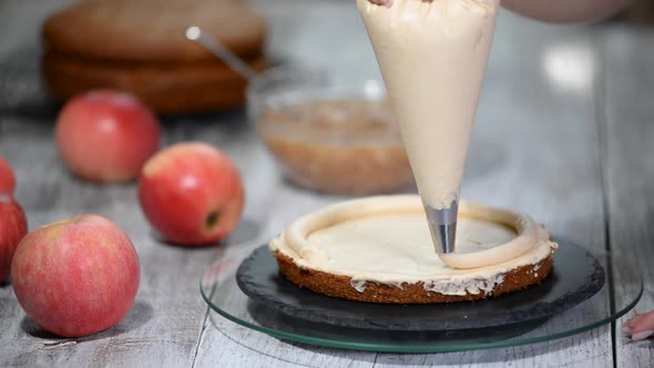 Unrecognizable female pastry cook squeezing cream on appetizing layer cake in kitchen alt