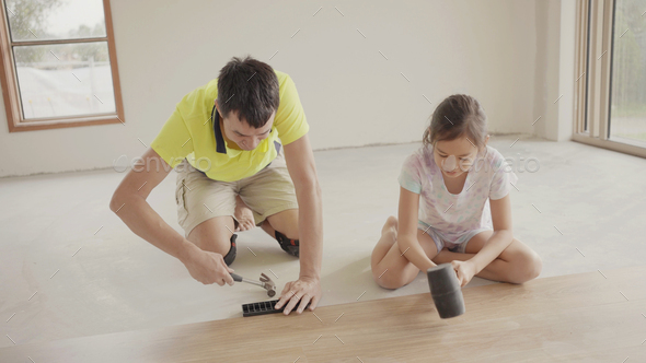 Father teaching daughter to install floor, house renovation project, homeschooling concept