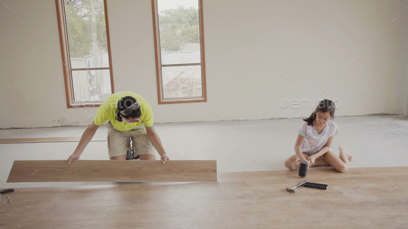 Father teaching daughter to install floor, house renovation project, homeschooling concept