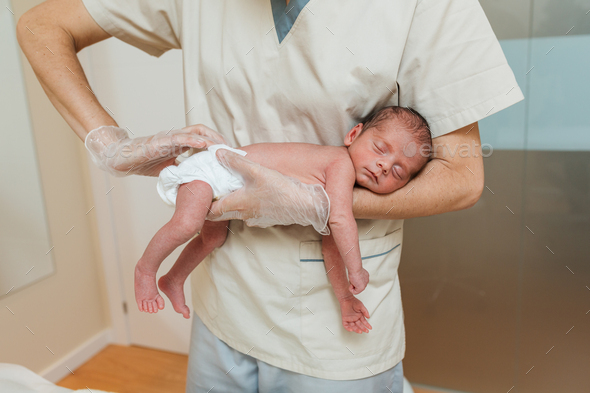Professional physiotherapist performing an induction of sacral mobility in a newborn