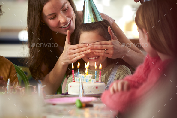 Girl With Candles On Birthday Cake At Surprise Party With Parents And Friends At Home