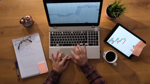 Working man with laptop is checking the tables and starts typing