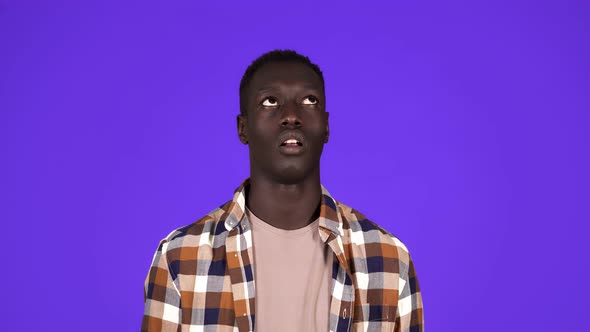 Portrait of Darkskinned Young Man Rolling His Eyes Up Isolated on Blue Background alt