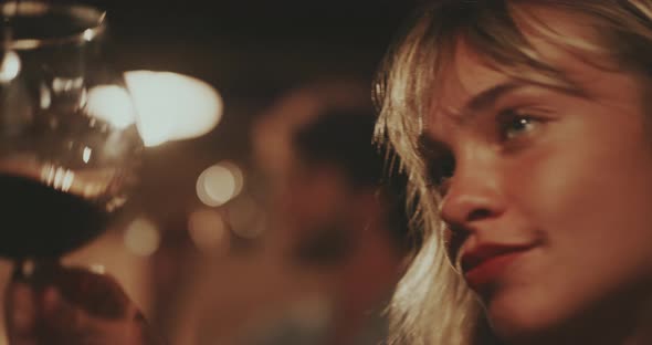 Young blonde woman taking a sip of red wine  alt