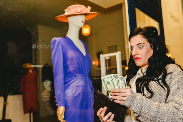 Woman with sad expression when not having enough money in dollars in her wallet to buy clothes. - Stock Photo - Images