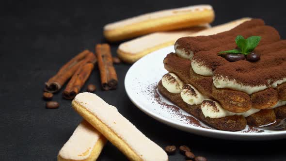Classic Tiramisu Dessert on Ceramic Plate and Savoiardi Cookies on Concrete Background alt