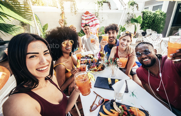 Multiracial group of friends enjoying meal having backyard dinner party