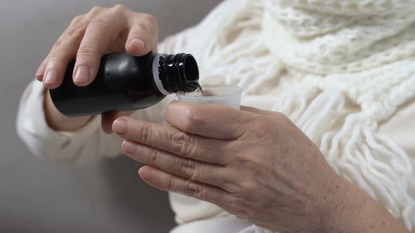 Mature Woman in Scarf Taking Disgusting Cough Syrup, Medicine for Flu Treatment