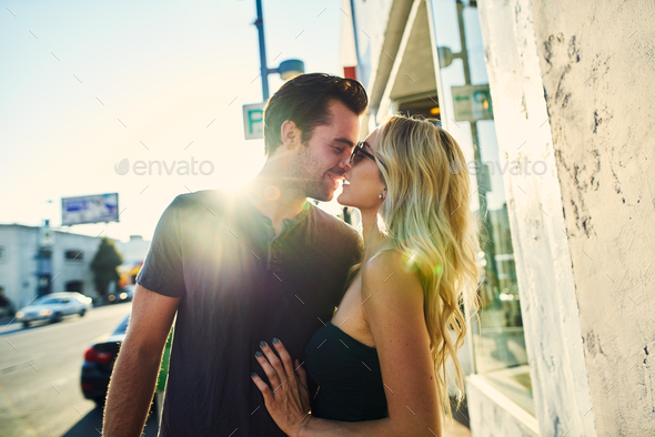 romantic couple kissing on sidewalk in los angeles Stock Photo by