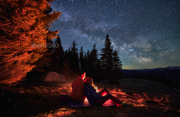 Pleasant rest of two hikers under open starry sky.