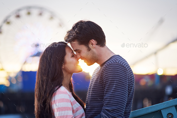 romantic couple in front of santa monica amusement park at sunset.