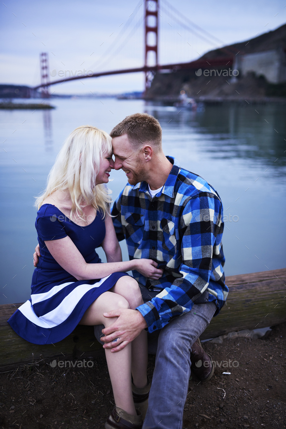 romantic couple cuddling by golden gate bridge at dusk Stock Photo by joshua_resnick