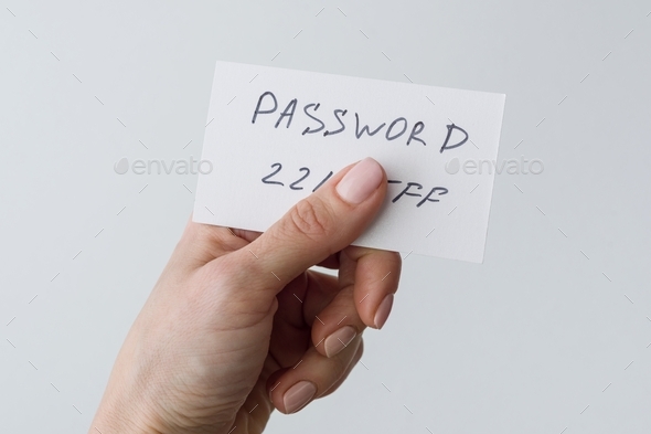 Woman's hand holds a password on paper, that covers the password with finger - Stock Photo - Images