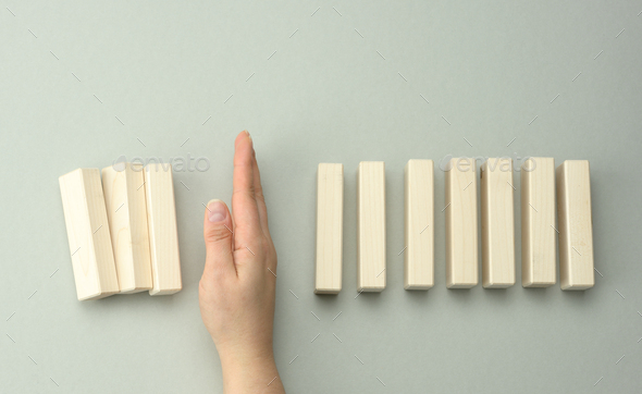 Woman\'s hand between the wooden blocks prevents most of it from falling