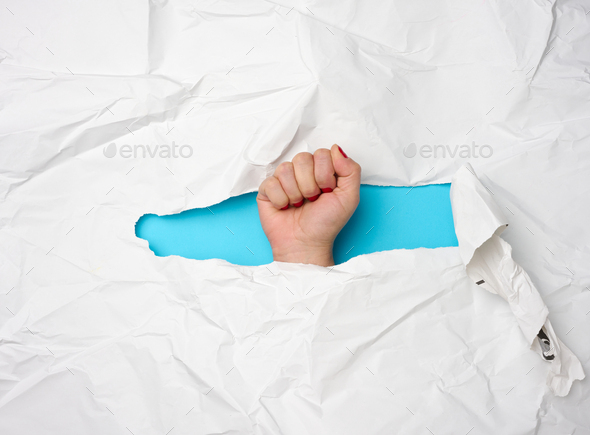 Female fist sticking out of torn hole on white paper, freedom
