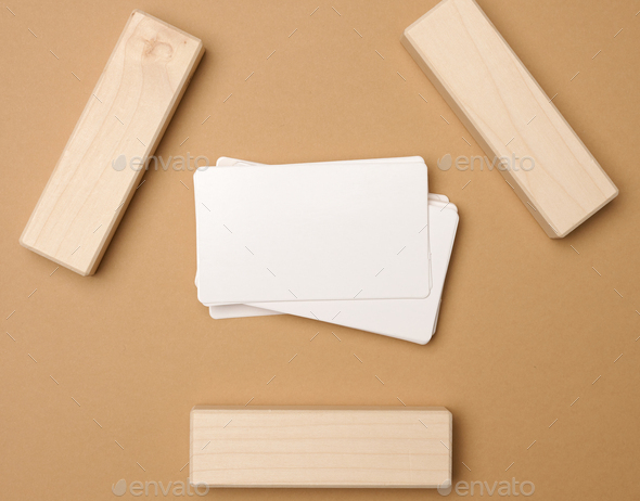 Stack of white rectangular business cards on a brown background, company branding