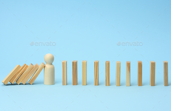 Wooden model of a man stops falling of wooden bars on a light blue background