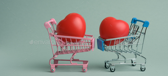 Red heart in a miniature metal trolley from the store on a gray background. Organ donation
