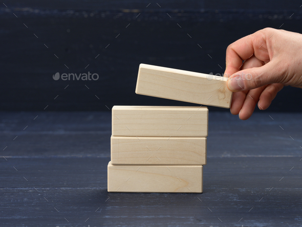 Female hand puts wooden blocks on top of each other. Goal planning concept, new knowledge, strategy