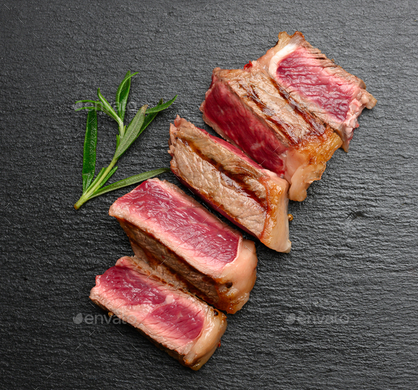 Sliced fried beef steak New York on a black background, degree of doneness rare