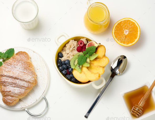 Plate with oatmeal and fruit, half a ripe orange and freshly squeezed juice