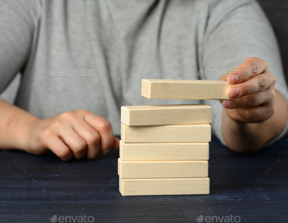 Female hand puts wooden blocks on top of each other. Goal planning concept, new knowledge