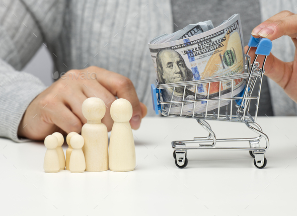 Woman sits at a table and a miniature cart with US dollars. Concept of savings, sale, tax