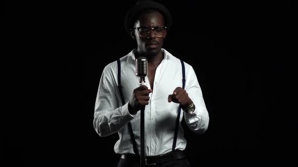 Man Singer Sings Into a Microphone and Dance. Black Background. Slow Motion alt