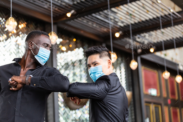 Diverse people wearing medical mask elbow bumping to greeting