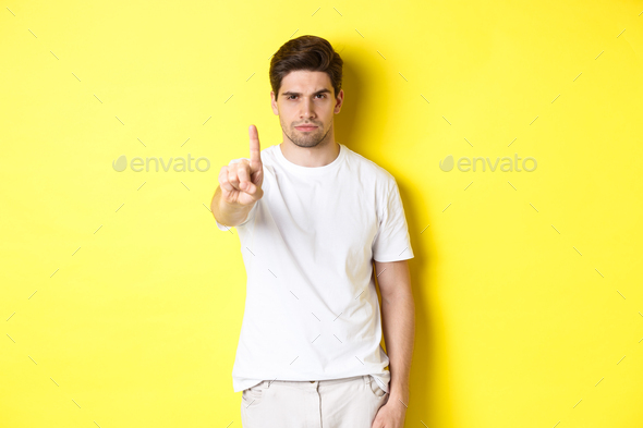 Confident man saying no, decline and prohibit something, showing one finger and frowning, standing