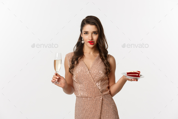 Party and celebration concept. Sexy woman in elegant dress, holding champagne and piece of cake