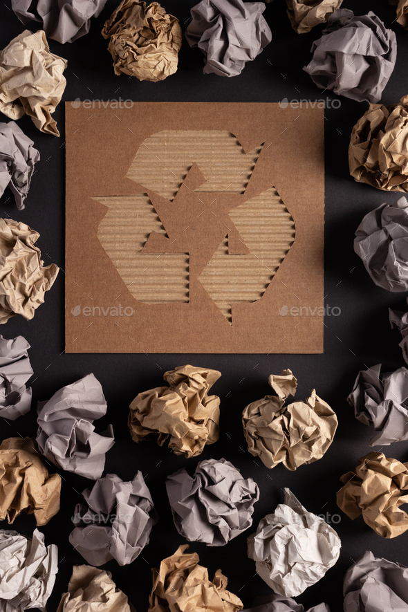 Recycle symbol and crumpled paper ball as background texture. Recycling concept on black paper