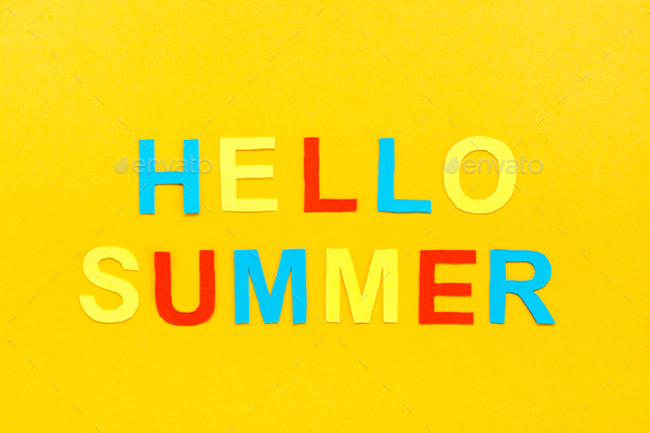 Hello summer. The inscription of colored carved letters on a yellow cardboard. Top view