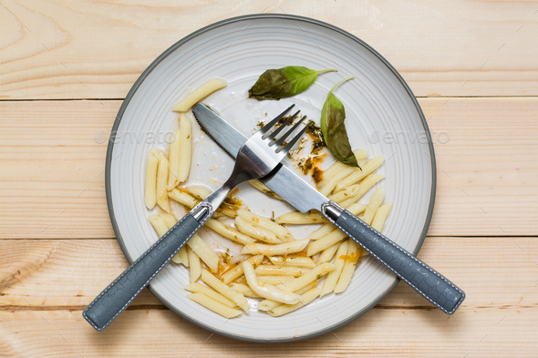 Stop wasting food. Leftover lunch and cutlery on a plate on a wooden background. Food waste concept