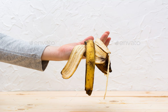Stop wasting food. Children\'s hand holds a rotten peel of a banana. Food waste concept.