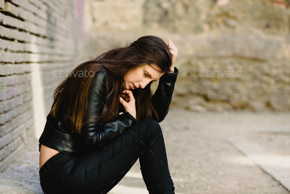 Sad young woman sitting on the floor when she is tired of fighting her problems - Stock Photo - Images